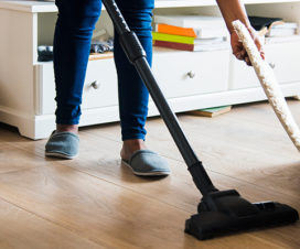 Woman vacuuming under a rug - Benefits of tidying up