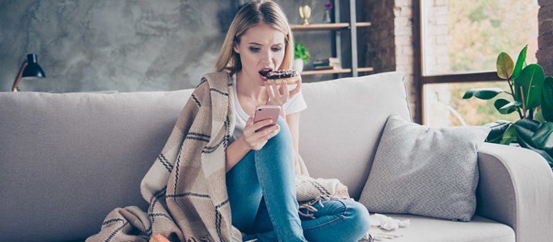 Woman on the couch eating a donut - How diet impacts mental health