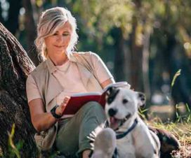 Woman relaxing and reading in a park with her dog - Activities to relieve stress