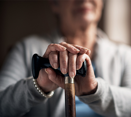 Image of elderly lady sitting while holding cane