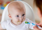 Baby eating avocado in a high chair - Tips for transitioning from baby food to solids