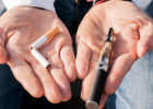Photo of a person holding a cigarette and vaping mechanism in their hands