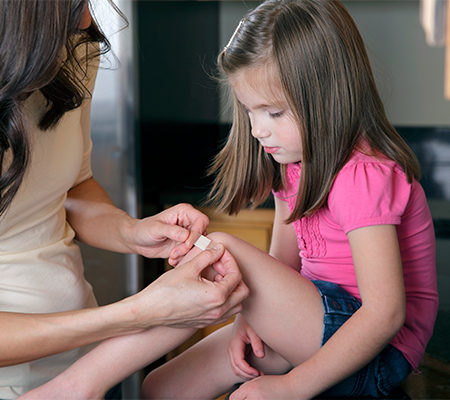 Photo of women putting band-aid on child's knee