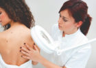 Photo of a provided checking a woman's back for skin tags