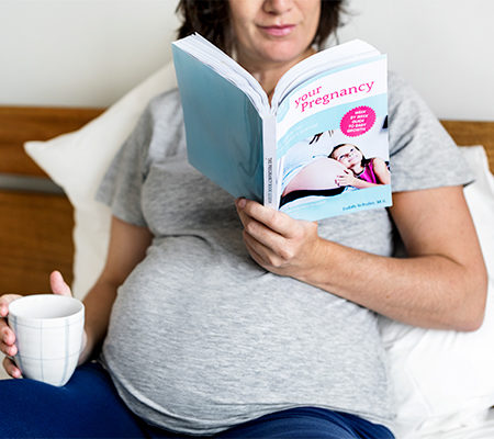 Photo of a pregnant woman reading a book