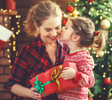 A child kissing her mom on the cheek after receiving a holiday present