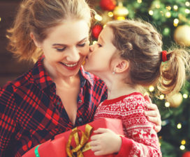 A child kissing her mom on the cheek after receiving a holiday present