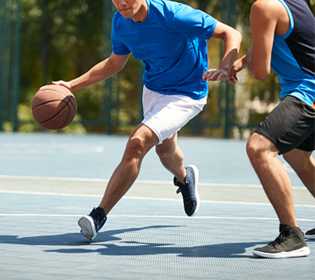 Two young men play basketball.
