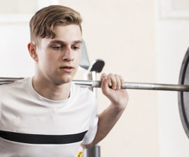 A young man lifts weights.