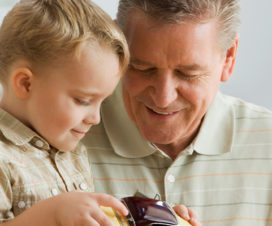 A man shows a toy car to his grandson.