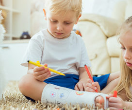 Two kids draw on a boy's cast.