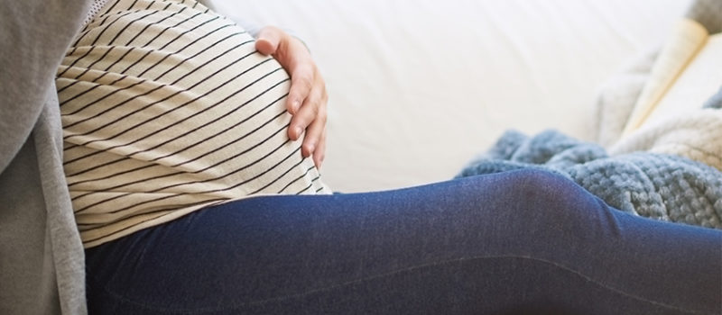 A pregnant woman sits on a couch.
