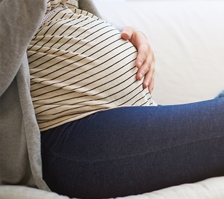 A pregnant woman sits on a couch.