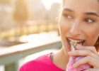 A woman eats a granola bar