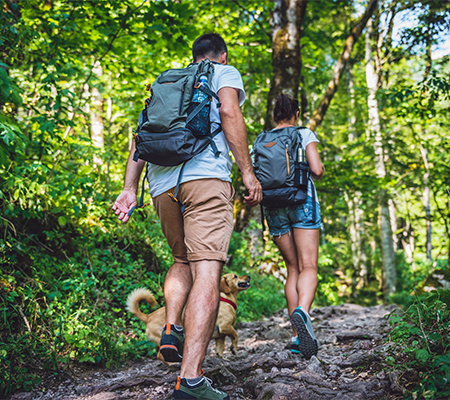 A couple goes hiking over rough terrain.