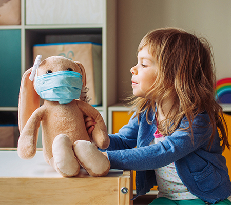 A girl plays with a stuffed rabbit.