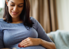 pregnant woman sitting on couch holding her stomach