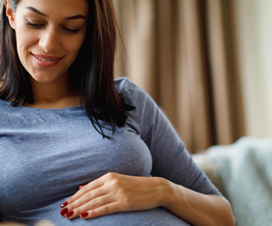 pregnant woman sitting on couch holding her stomach