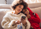 mom on phone sitting next to kid on couch