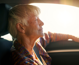 older woman sitting in car basking in the sunlight