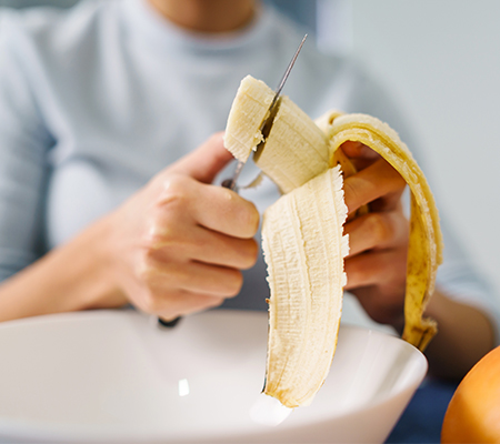 Image of woman cutting up a banana
