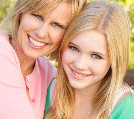 Portrait of a happy mother and her teenage daughter smiling. 