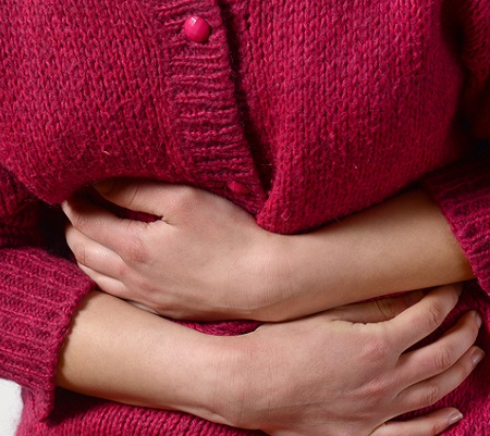Female in red sweater holding her stomach, acting as-if in pain.