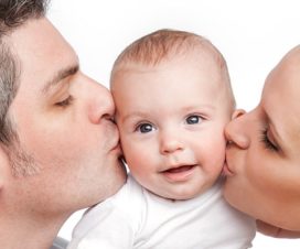parents kissing a baby
