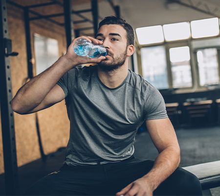 man in gym drinking a water bottle