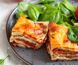 lasagna with spinach and a tomato on a plate
