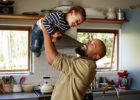 dad holding kid above his head in the kitchen