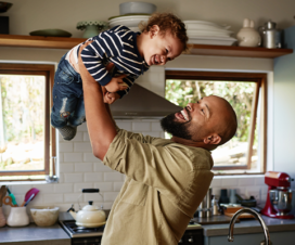 dad holding kid above his head in the kitchen