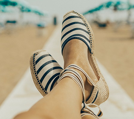 A person wearing summer shoes: striped sandals. 