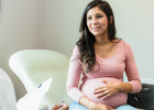 woman visibly pregnant holding stomach while talking to a doctor during an appointment