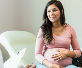 woman visibly pregnant holding stomach while talking to a doctor during an appointment