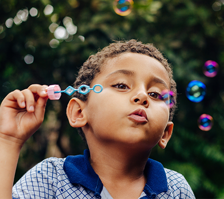 Little boy blowing bubbles learning about burn protection in children