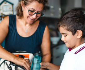 mom packing bag for young boy before he goes to school