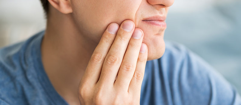 Man grabs his jaw in TMJ pain, wondering if physical therapy could help.