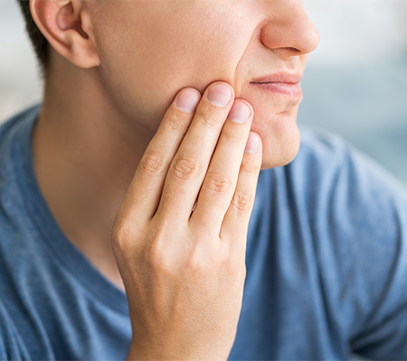 Man grabs his jaw in TMJ pain, wondering if physical therapy could help his TMD.