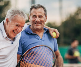 two men laughing while playing tennis
