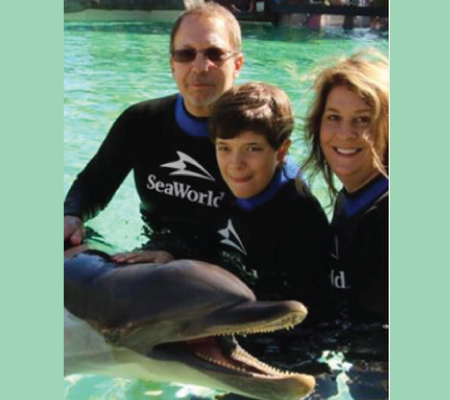 David and his family in the water with a dolphin