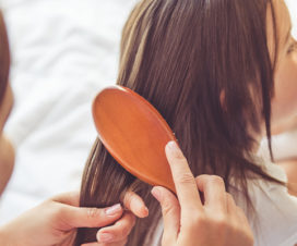 Parent brushing head lice on child, treat lice at home