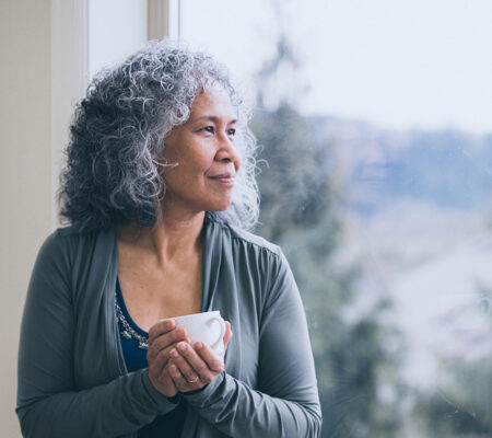 Middle-aged lady holding cup as she ponders how lower cortisol levels impact her health 