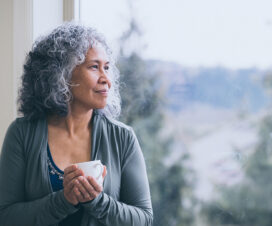 woman holding coffee cup as she looks out the window
