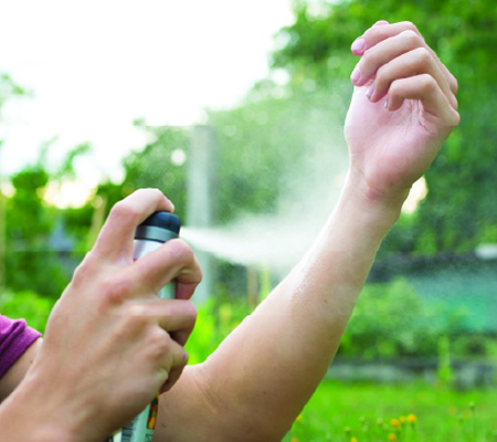 person applying bug spray on skin questioning if deet is safe and its health risks