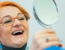 Woman looking at her dental implants in a mirror.