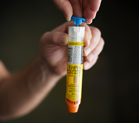 person holding an EpiPen a common initial anaphylaxis treatment