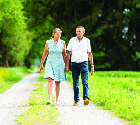 An older couple walking hand-in-hand outside on a path discussing return to use for alcohol or drugs