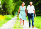 An older couple walking hand-in-hand outside on a path