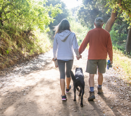 A couple walking outside on a trail with their dog - Advance Directives